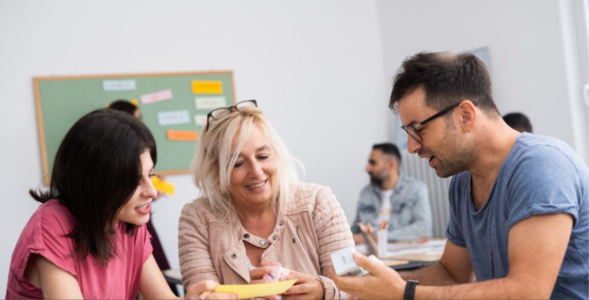 Students speaking together in an A2 German course in Frankfurt am Main, small group class with teacher in the background