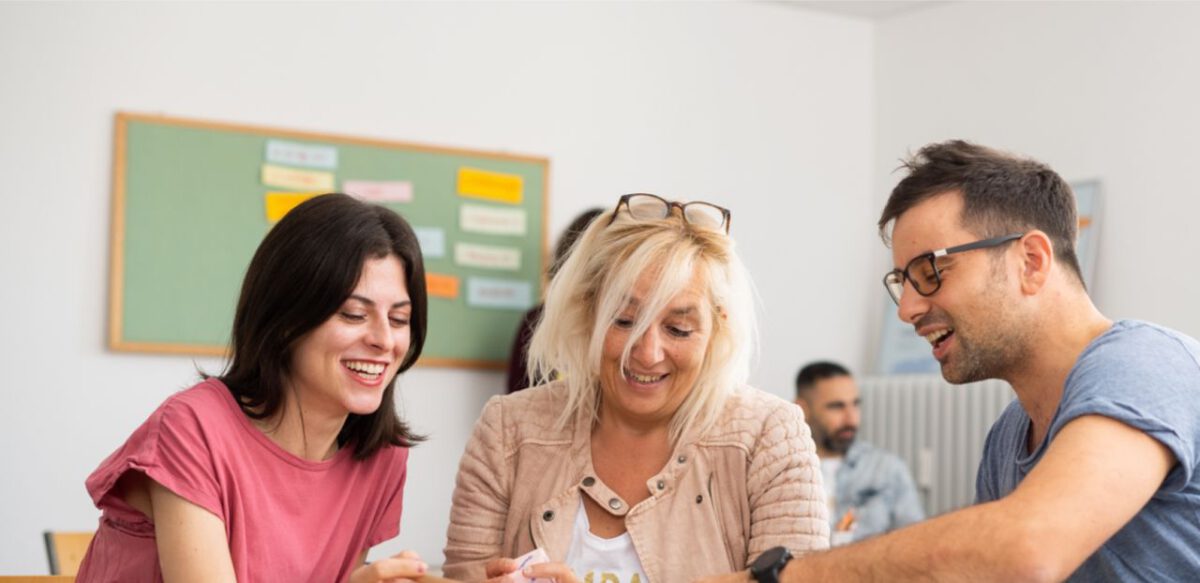 Teilnehmende diskutieren im C1 Deutschkurs in Frankfurt am Main, kleine Lerngruppe mit Lehrerin im Hintergrund