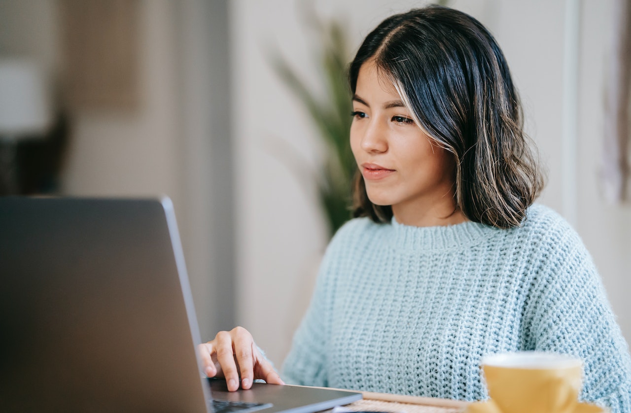 Frau am Computer mit hellblauem Pullover – Symbol für konzentriertes Deutschlernen im Berufssprachkurs