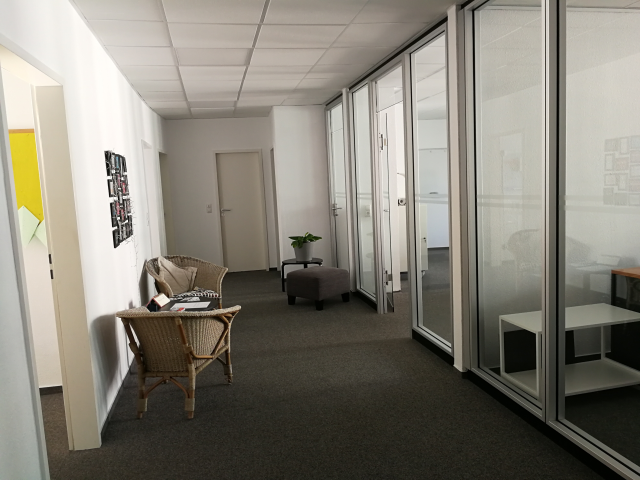 Entrance area of the SprachPassion language school in Frankfurt, Schäfergasse 50: two armchairs with a table on the left, a stool and a plant on the right. From here, the classrooms for the German intensive course in Frankfurt branch off.”