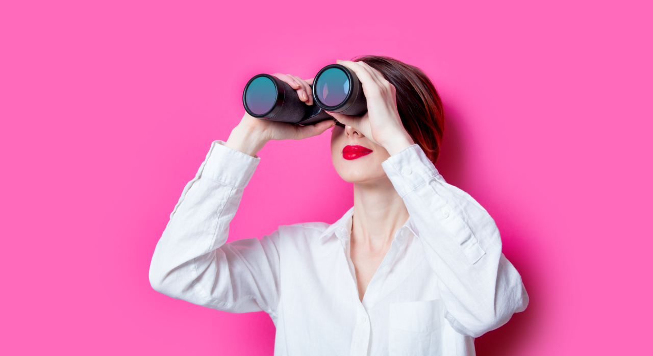 Woman looking through binoculars – symbolizing the observation of goals in learning German in Frankfurt.